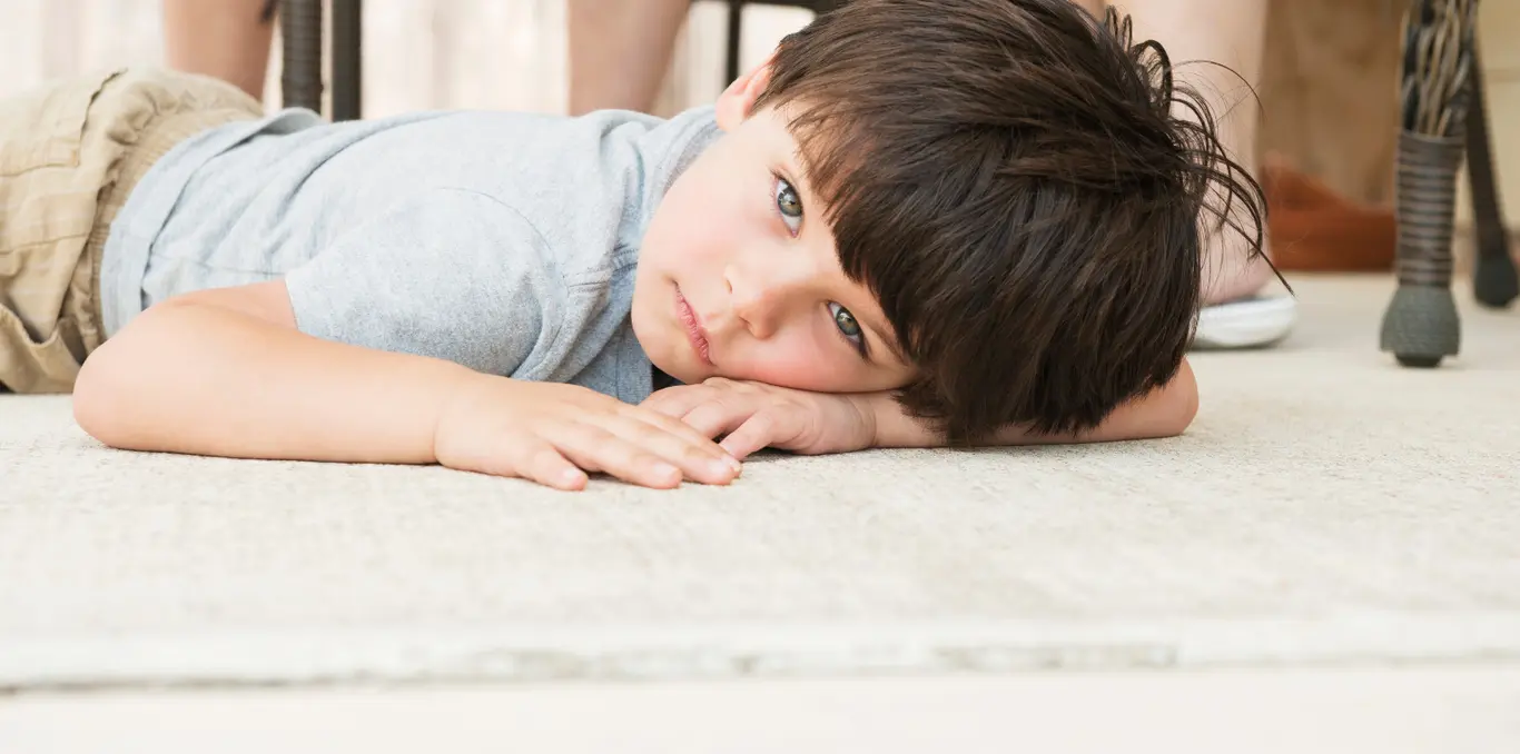 smutny i zmartwiony chłopiec leżący na brzuchu na podłodze
